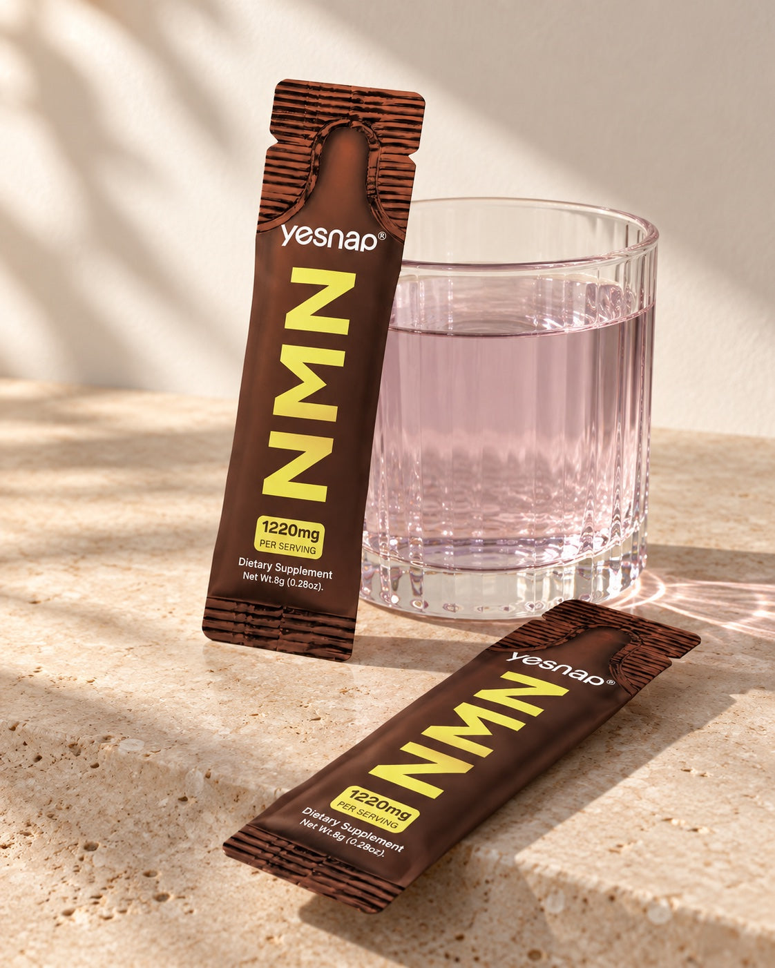 Yesnap NMN individual packets beside a glass of grape-colored water